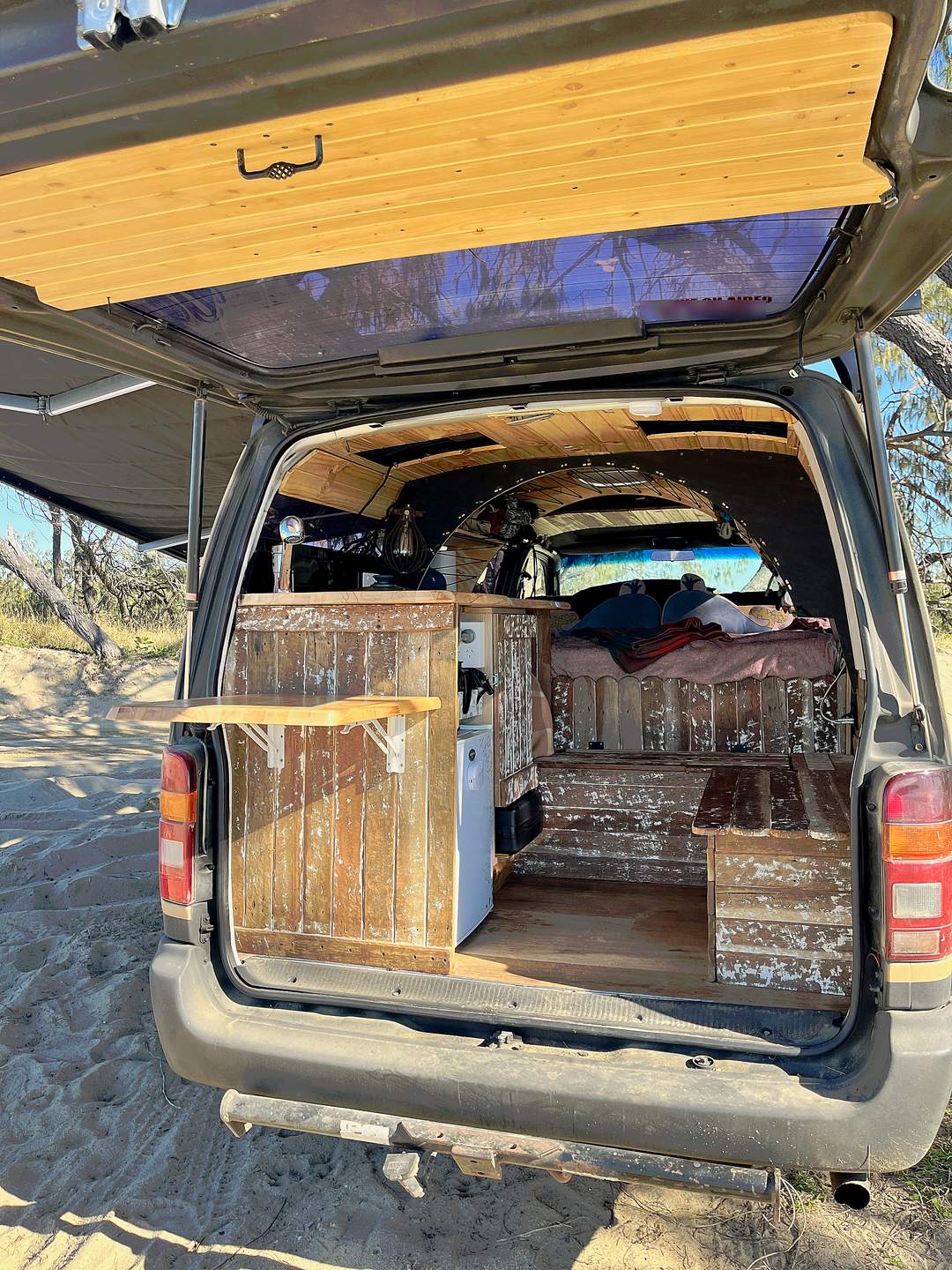 Rear doors open on sandy track with awning up