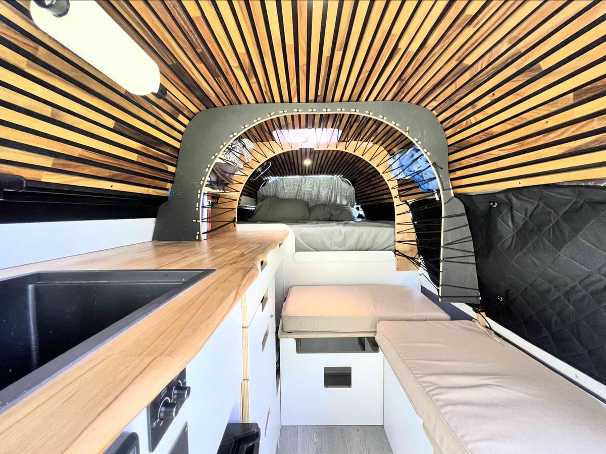 Interior arch — timber slat ceiling, bench seating, bed beyond