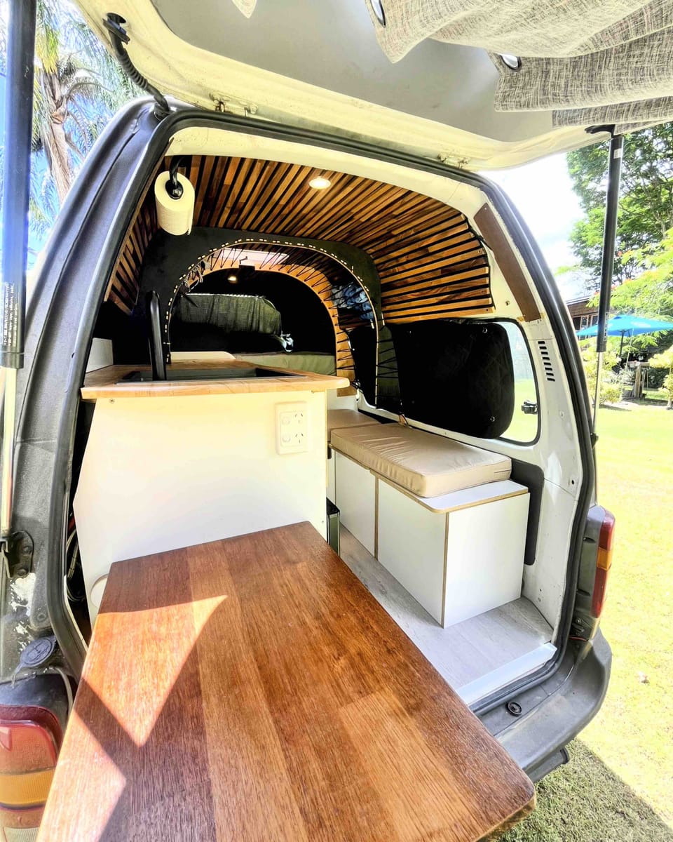 Rear doors open in sunshine — fold-out table and timber interior