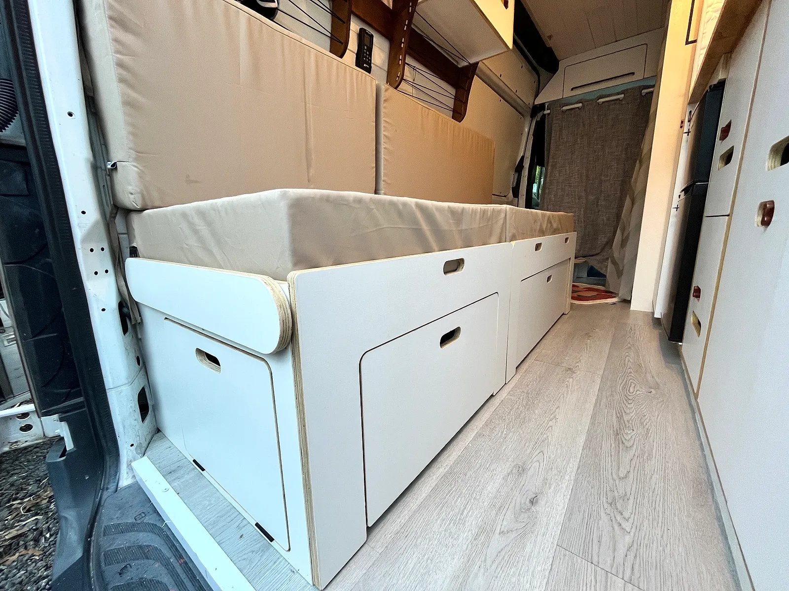 White comb bed installed in a campervan — fully extended into a sleeping platform with mattress in place