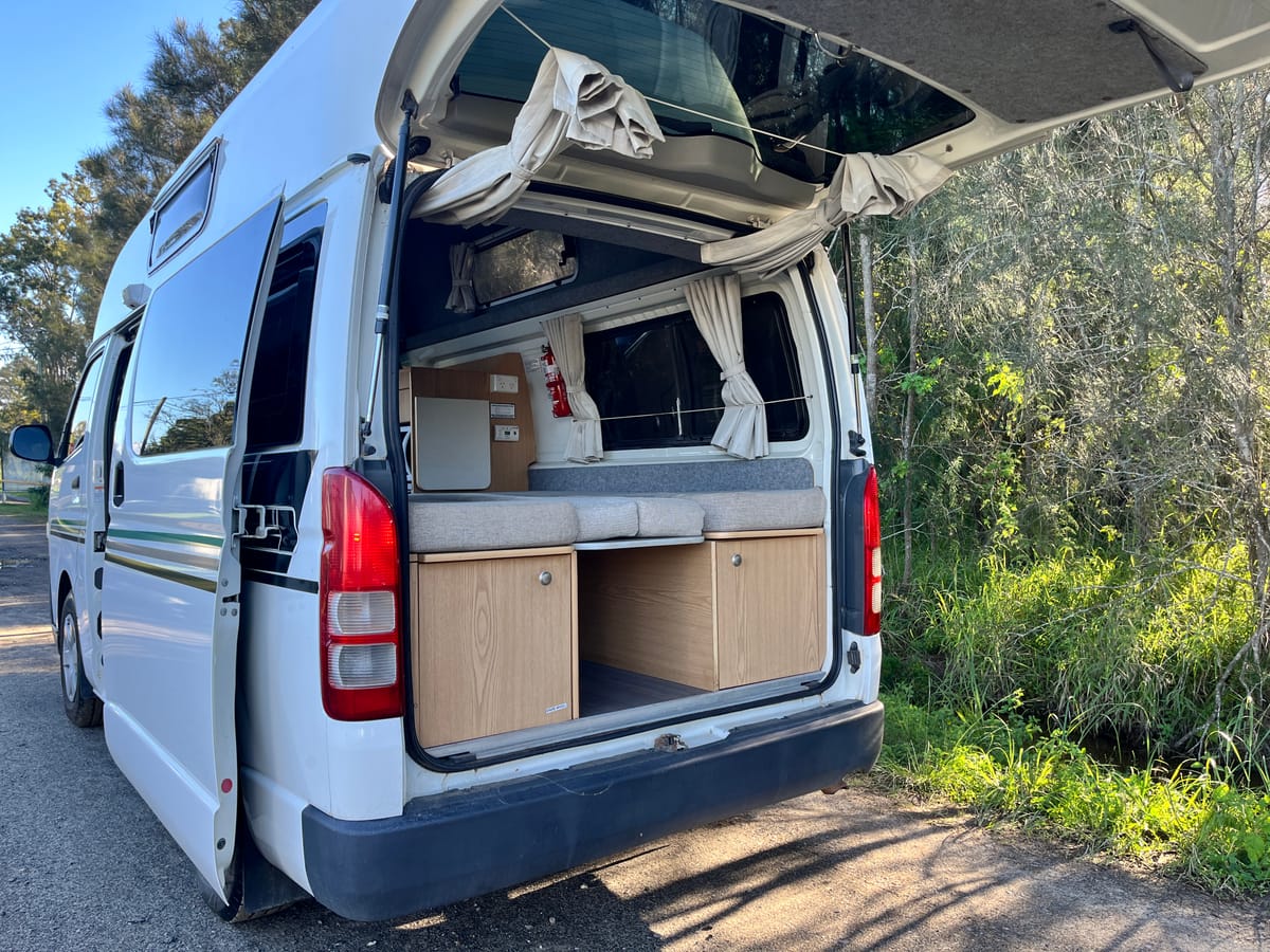 Toyota Hiace hitop camper, rear doors open with comb bed made up, midday