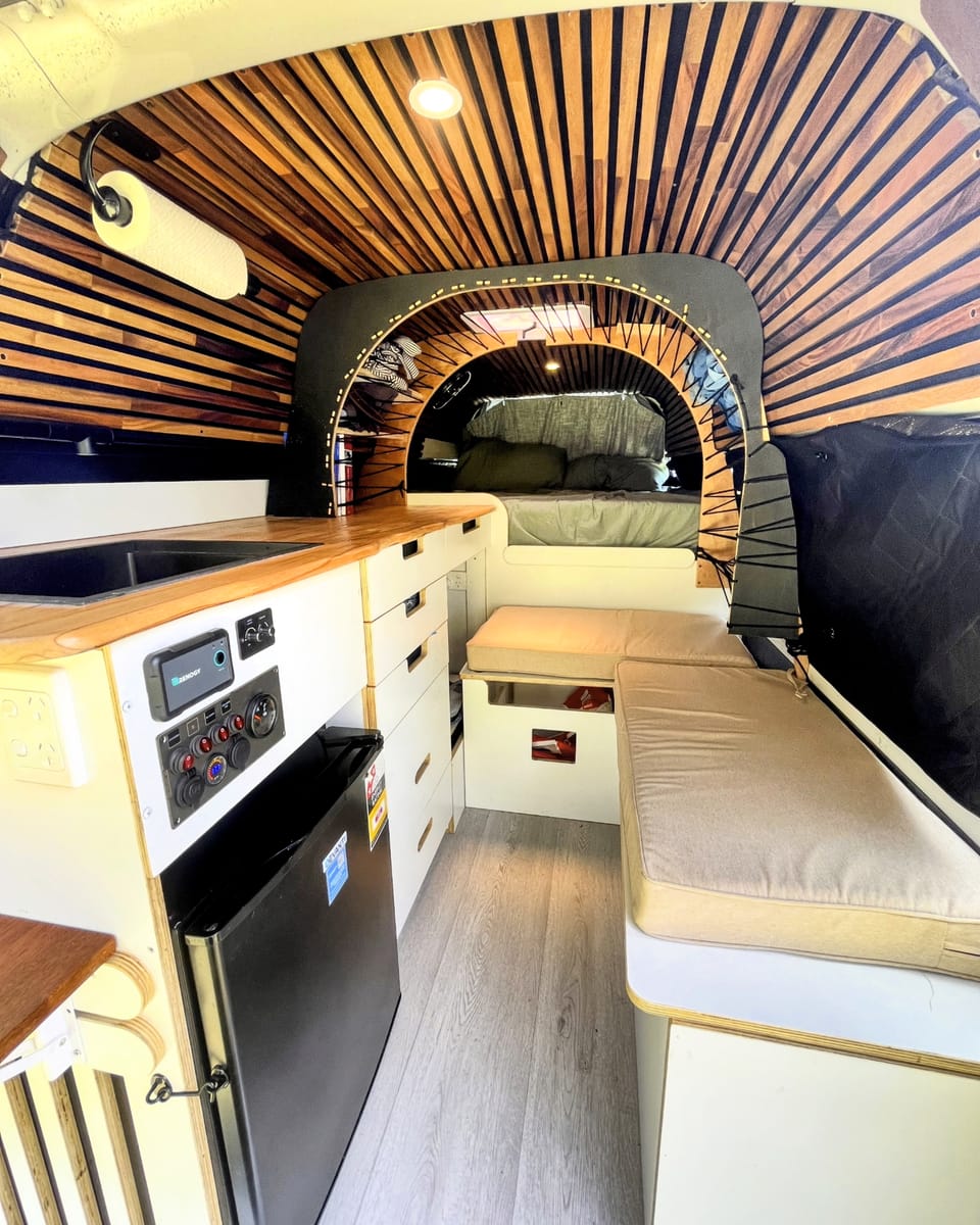 Custom Hiace interior with slatted-wood ceiling and rear queen bed